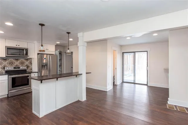 a kitchen with stainless steel appliances white cabinets a sink a stove a refrigerator and a oven with wooden floor