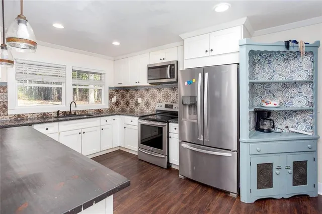 a kitchen with stainless steel appliances granite countertop a sink a stove and a wooden floor