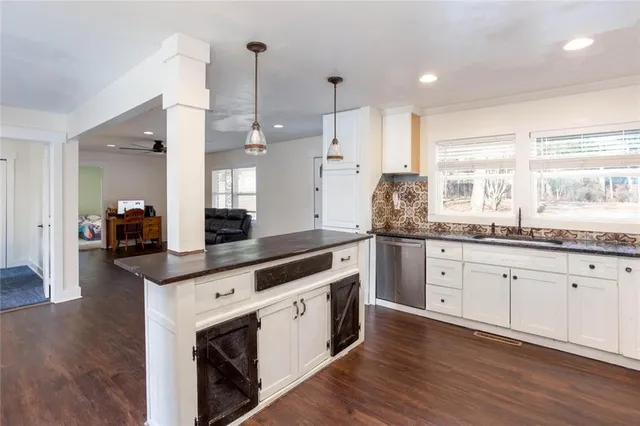 a kitchen with granite countertop cabinets stainless steel appliances a sink and wooden floor
