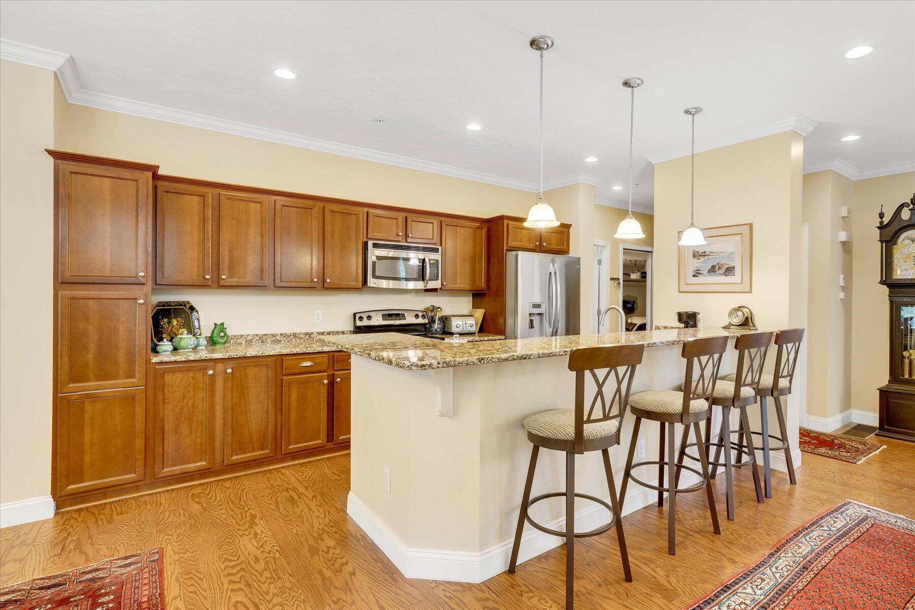 17 Chadwick Court Mashpee, MA 02649 - Photo 10 of 40 a kitchen with stainless steel appliances kitchen island granite countertop a refrigerator a stove top oven a sink and a dining table with wooden floor