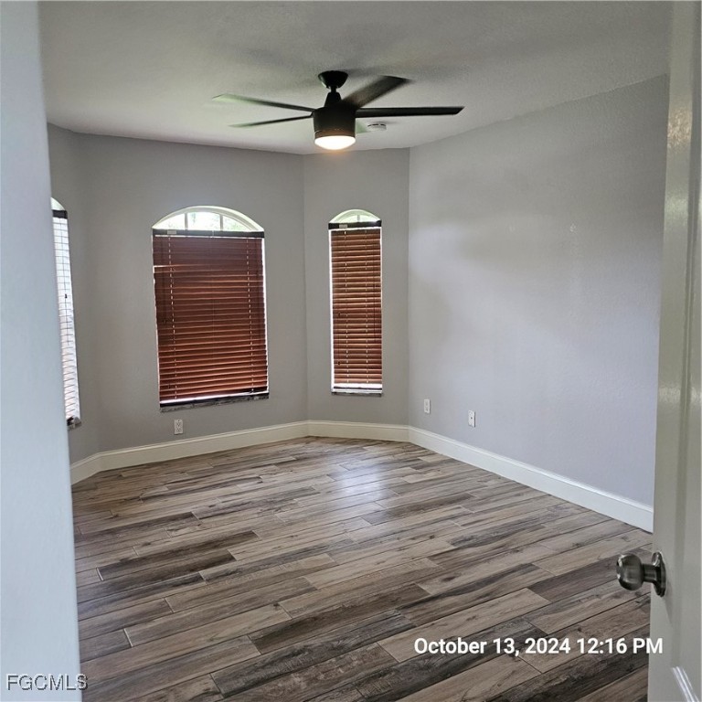 3780 Randall Boulevard Naples, FL 34120 - Photo 6 of 12 an empty room with wooden floor chandelier fan and windows