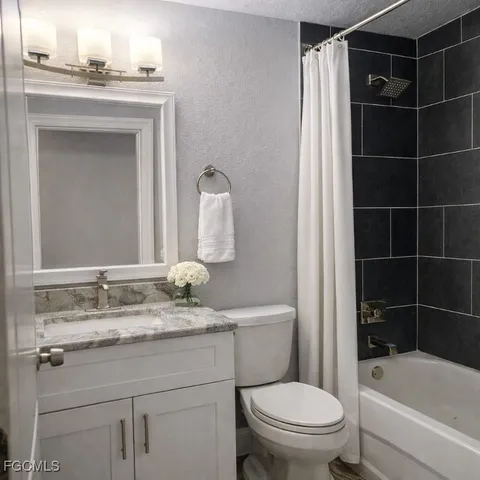 a bathroom with a granite countertop toilet a sink and a bathtub