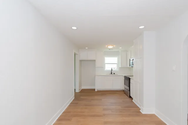 a view of a kitchen with a sink and dishwasher a refrigerator with wooden floor