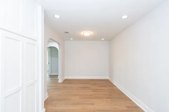 an empty room with wooden floor and entrance
