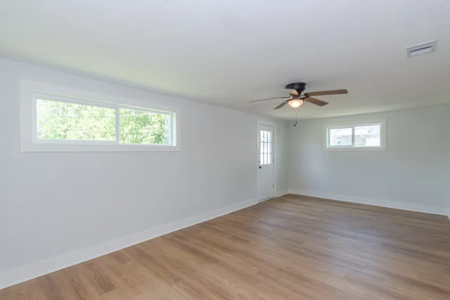 a view of an empty room with wooden floor and a window