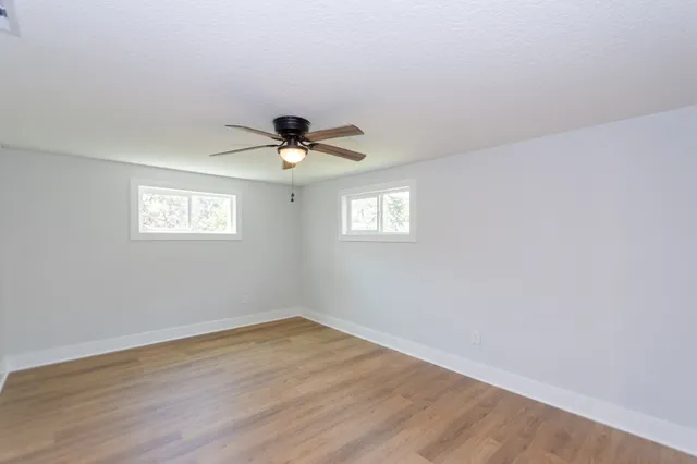 a view of empty room with wooden floor and fan