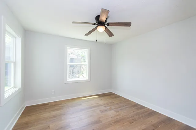 a view of empty room with wooden floor and fan