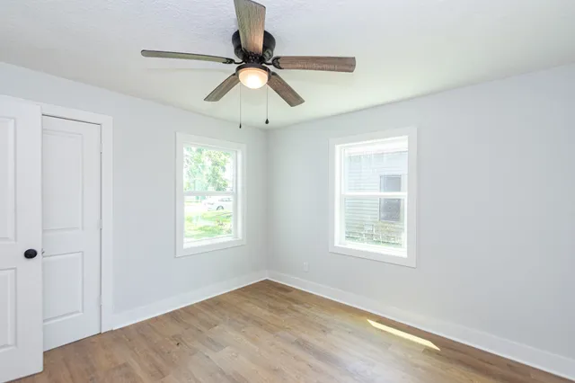 a view of an empty room with wooden floor and window
