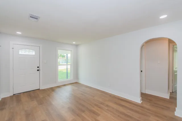 an empty room with wooden floor and windows