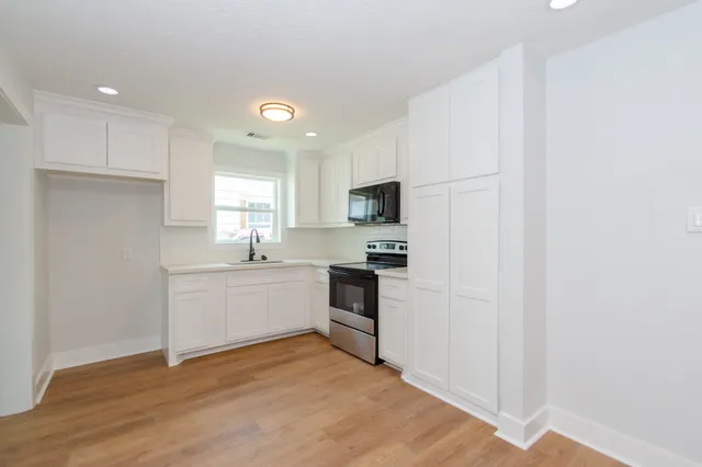 a kitchen with a refrigerator stove and white cabinets