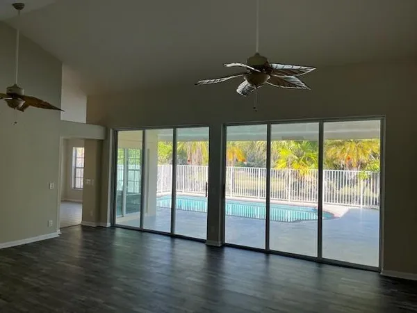 a view of empty room with wooden floor and fan