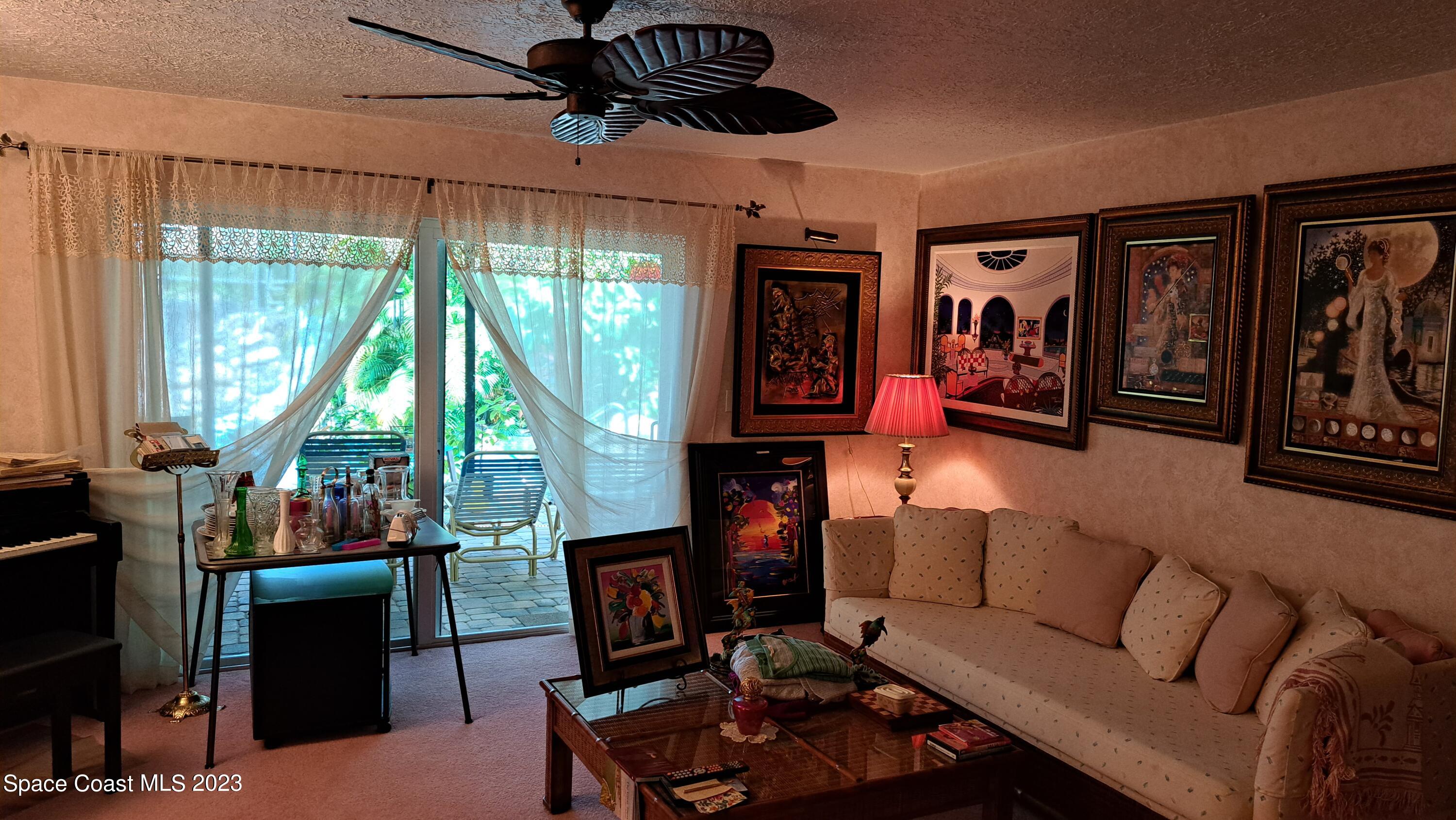 1083 Pineapple Avenue Northeast Palm Bay, FL 32905 - Photo 16 of 26 a living room with furniture a flat screen tv and a floor to ceiling window