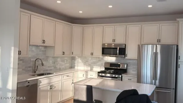 a kitchen with a refrigerator and white cabinets