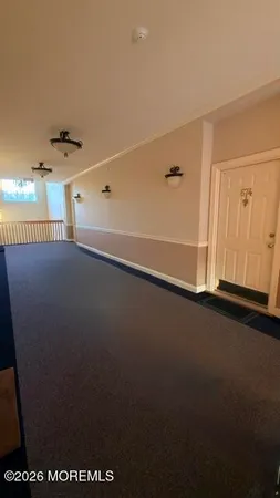 a view of an empty room with window and chandelier fan