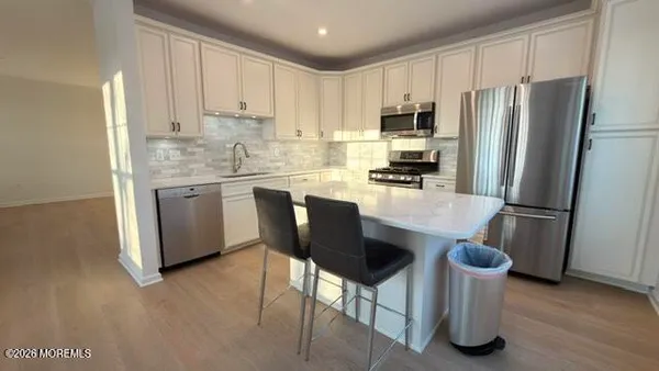 a kitchen with stainless steel appliances granite countertop a refrigerator a stove a sink a dining table and chairs