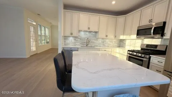 a kitchen with granite countertop a stove a sink a microwave and wooden cabinets