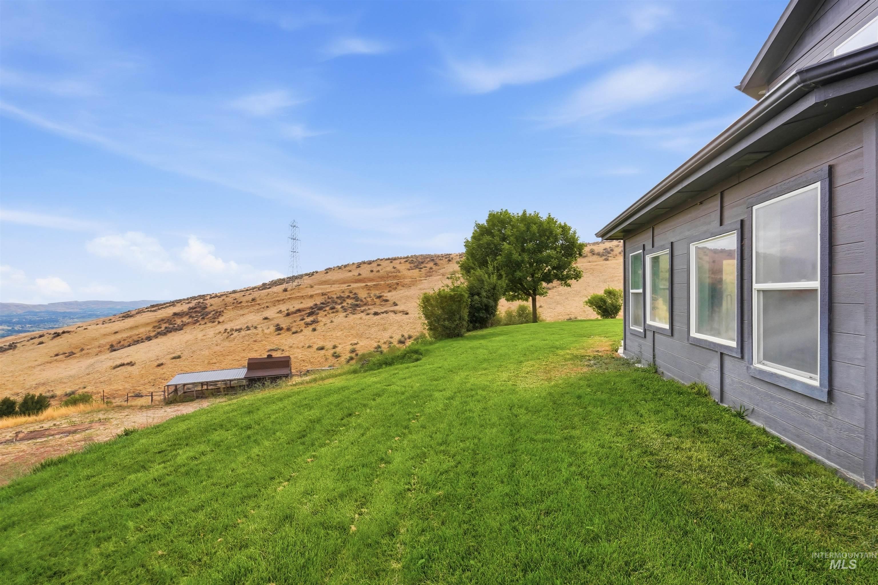 3645 Butte Road Emmett, ID 83617 - Photo 35 of 39 Expansive green lawn with mountain backdrop, house exterior with horizontal siding, and multiple windows