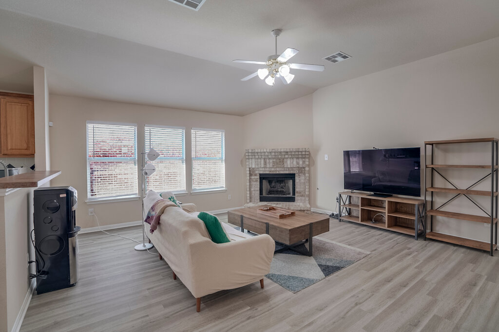 2724 Kickapoo Cavern Drive Pflugerville, TX 78660 - Photo 5 of 24 A comfortable gathering space boasts a prominent brick fireplace and warm wood-look flooring.