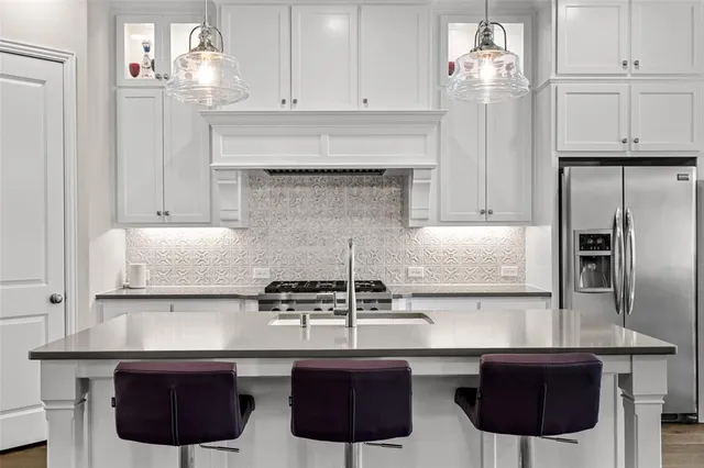 a kitchen with granite countertop a stove a sink a refrigerator a dining table and chairs with wooden floor