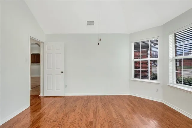 a view of an empty room with window and chandelier fan