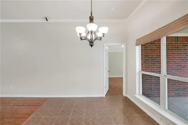 an empty room with wooden floor chandelier fan and windows