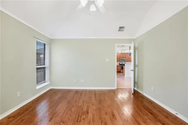 a view of empty room with wooden floor and fan