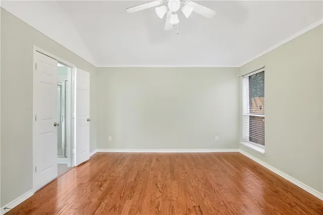 a view of empty room with wooden floor and fan