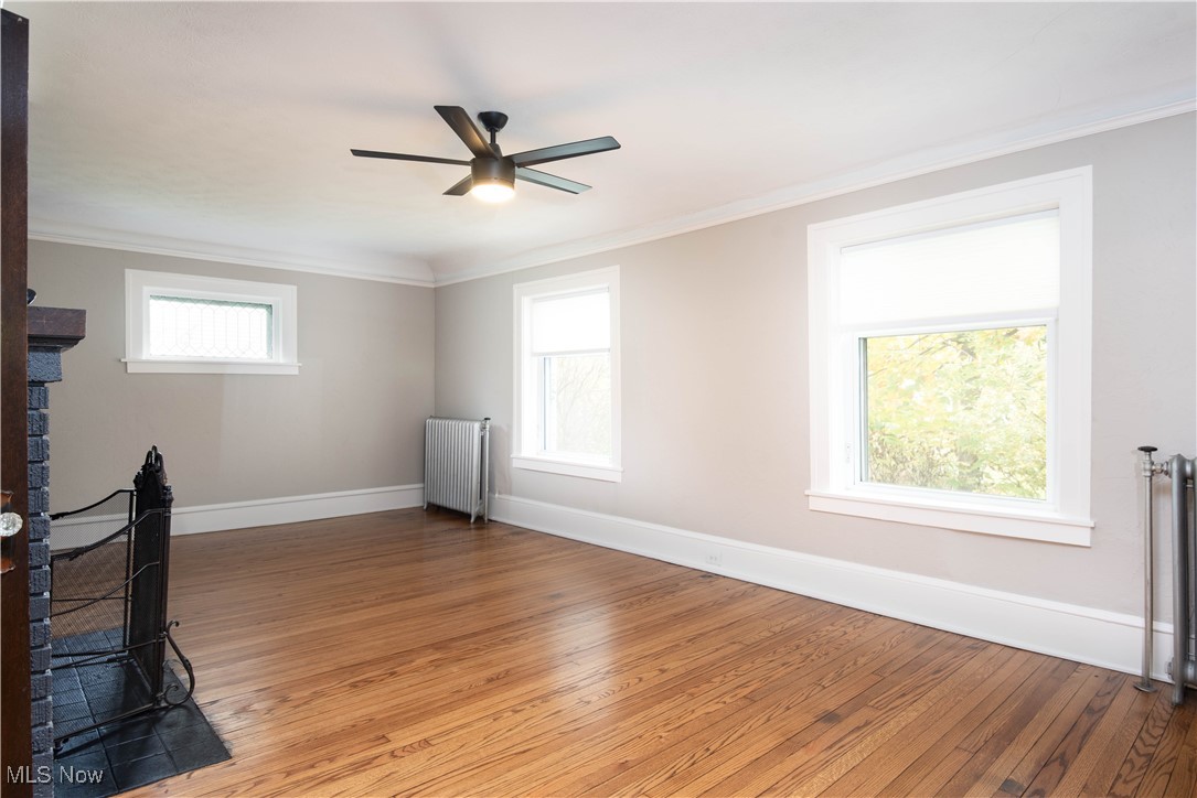 7003 Brecksville Road Independence, OH 44131 - Photo 4 of 35 Unfurnished living room featuring crown molding, hardwood / wood-style floors, radiator heating unit, radiator, and ceiling fan