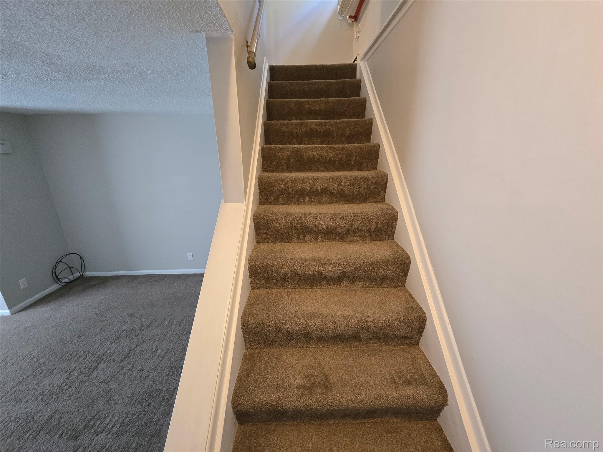 27780 Reo Road Grosse Ile, MI 48138 - Photo 8 of 18 Carpeted staircase featuring a painted handrail and neutral wall tones