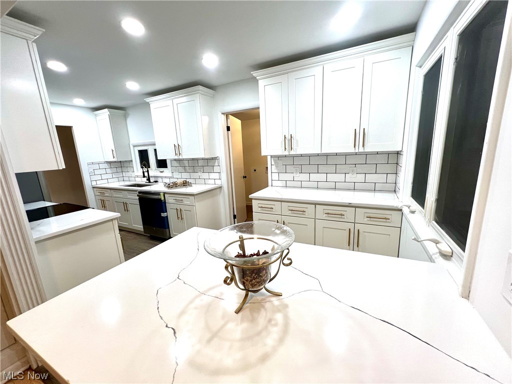 7687 Ragall Parkway Cleveland, OH 44130 - Photo 12 of 37 Kitchen with light stone counters, white cabinets, backsplash, sink, and dishwasher