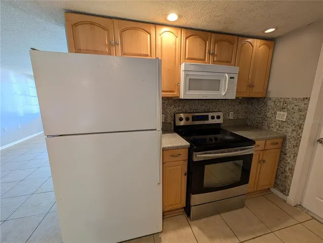 a kitchen with stainless steel appliances granite countertop a refrigerator a stove a sink and a microwave