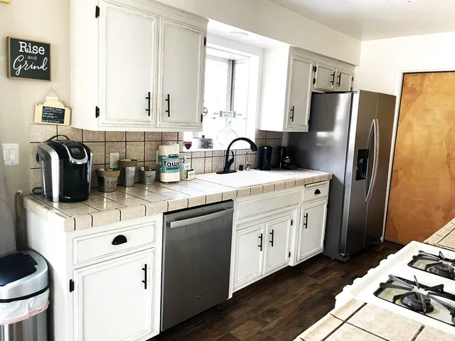 a kitchen with stainless steel appliances a sink a stove a refrigerator a counter space and cabinets