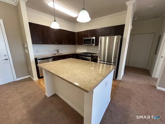 a kitchen with stainless steel appliances granite countertop a sink a refrigerator and a stove