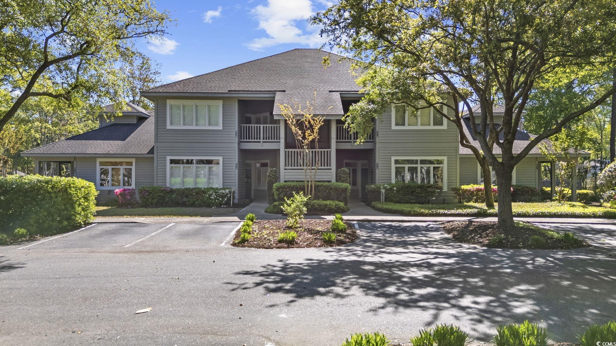 View of front of home with roof with shingles, a balcony, and uncovered parking