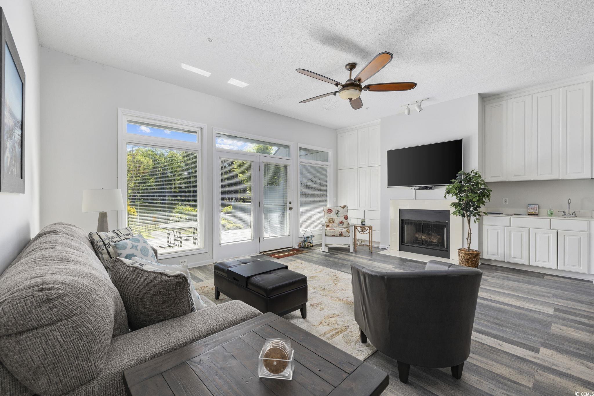 1221 Tidewater Drive, Unit 412 North Myrtle Beach, SC 29582 - Photo 11 of 36 Living area with a fireplace, ceiling fan, a textured ceiling, and wood finished floors