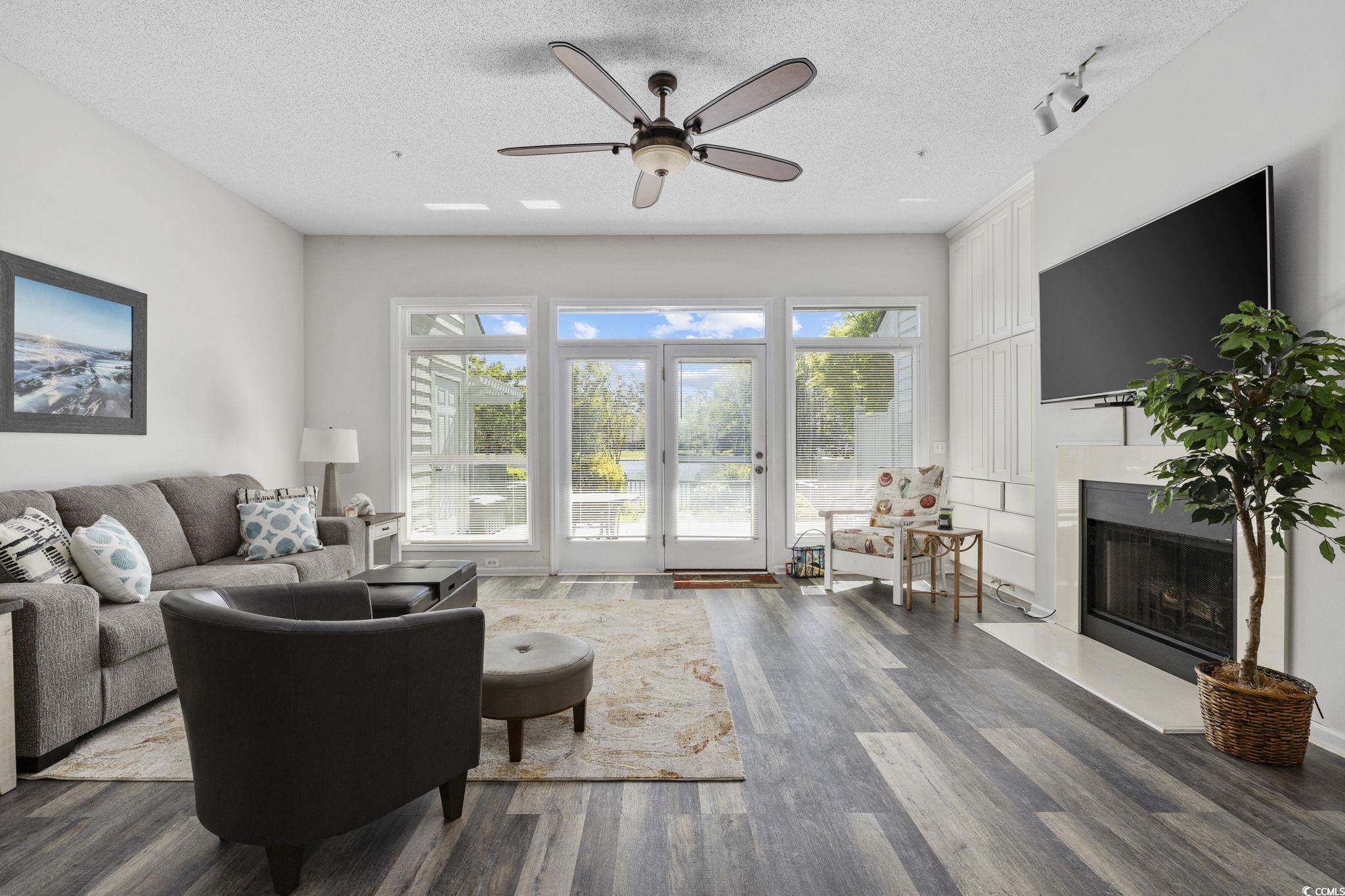 1221 Tidewater Drive, Unit 412 North Myrtle Beach, SC 29582 - Photo 14 of 36 Living room with a fireplace, wood finished floors, a textured ceiling, a ceiling fan, and plenty of natural light
