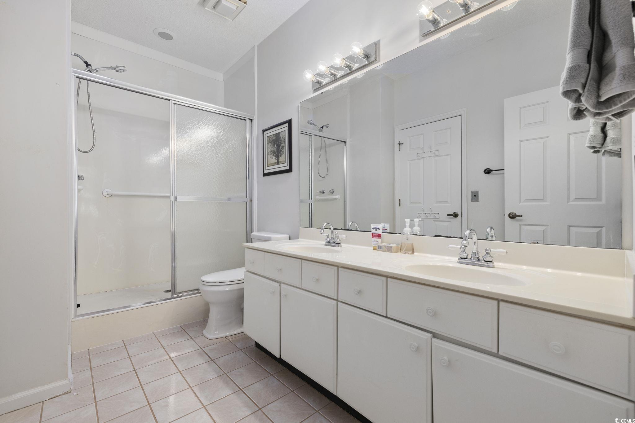 1221 Tidewater Drive, Unit 412 North Myrtle Beach, SC 29582 - Photo 18 of 36 Full bathroom featuring double vanity, a stall shower, and light tile patterned floors