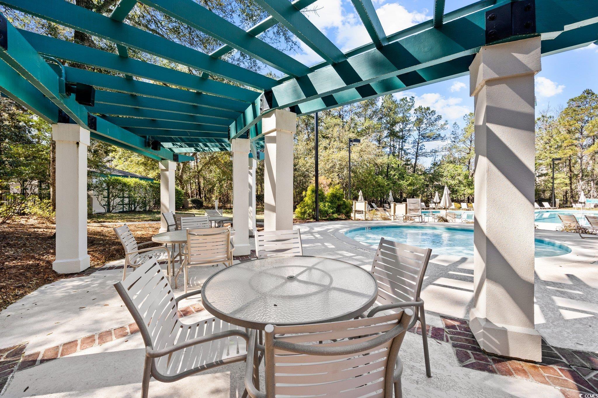 1221 Tidewater Drive, Unit 412 North Myrtle Beach, SC 29582 - Photo 32 of 36 Community pool featuring a patio area and view of wooded area