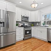 a kitchen with white cabinets stainless steel appliances and wooden floor