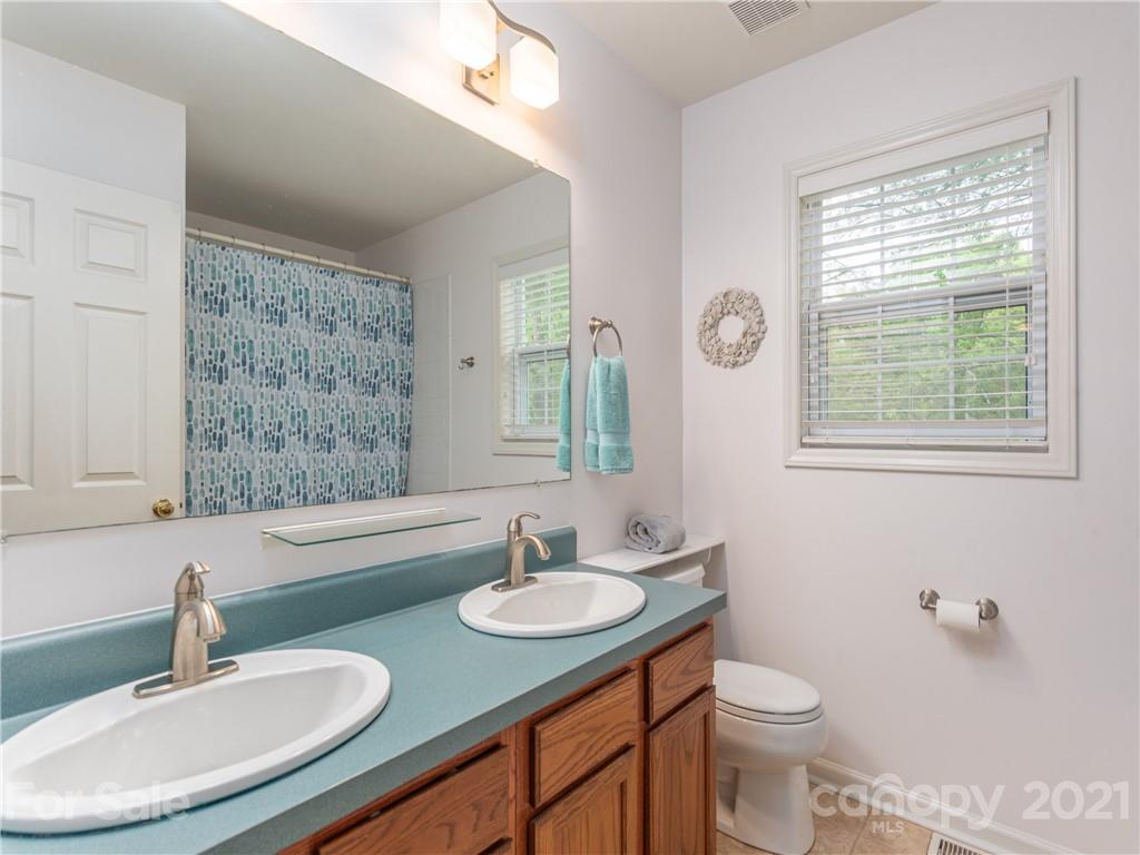 100 Ridgeline Road Clyde, NC 28721 - Photo 13 of 26 a bathroom with a granite countertop sink toilet a mirror and a window