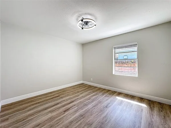 an empty room with wooden floor and window