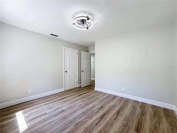 an empty room with wooden floor and windows