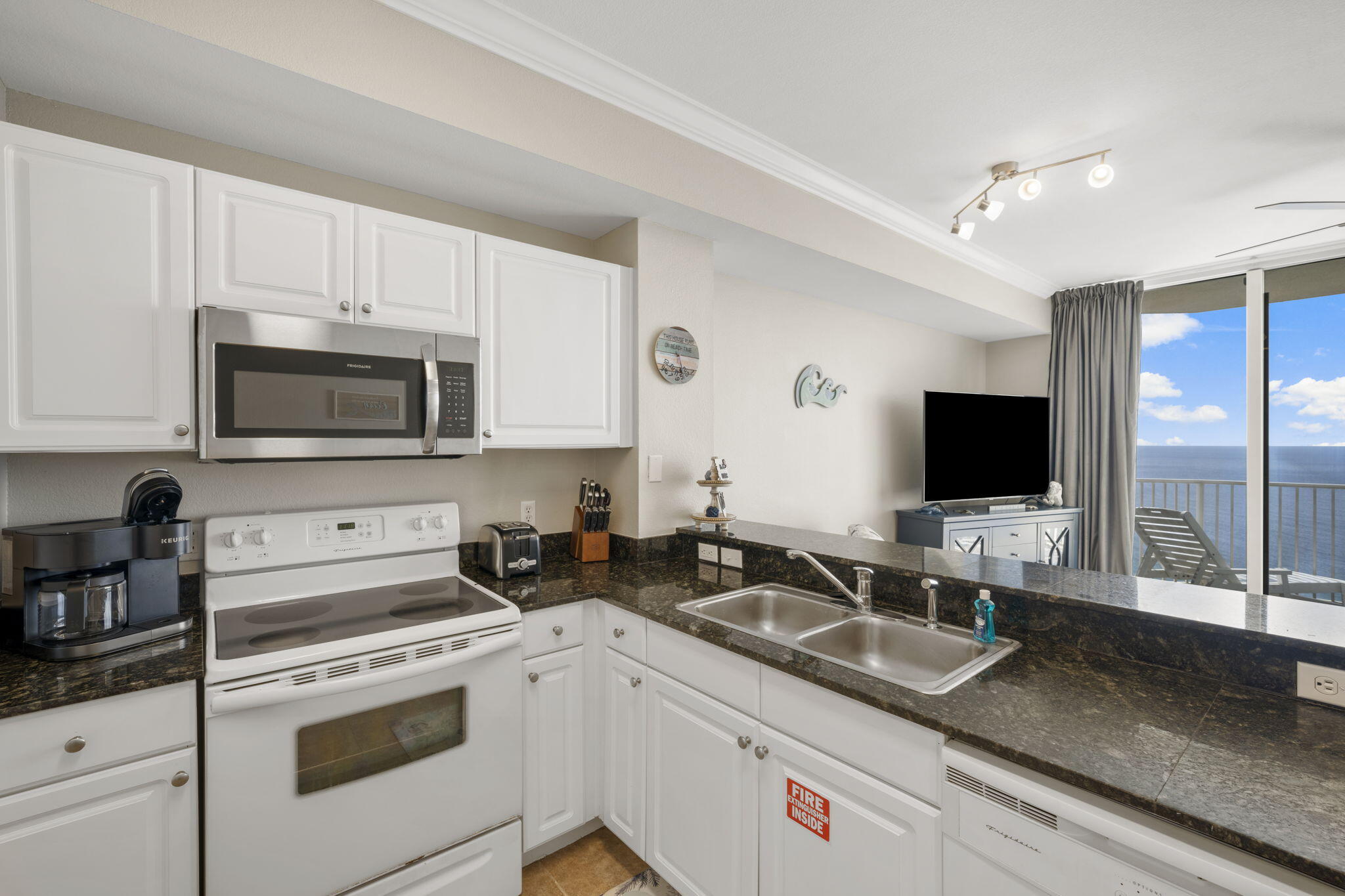 16819 Front Beach Road, Unit 2116 Panama City Beach, FL 32413 - Photo 9 of 51 a kitchen with granite countertop a sink and white cabinets