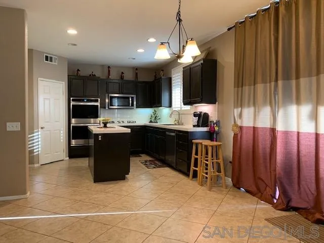 38325 Encanto Road Murrieta, CA 92563 - Photo 7 of 17 a kitchen with kitchen island granite countertop a sink counter top space appliances and cabinets