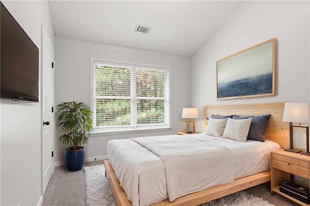 199 Mount Moriah Road Ball Ground, GA 30107 - Photo 26 of 39 a bedroom with a bed potted plants and a flat screen tv