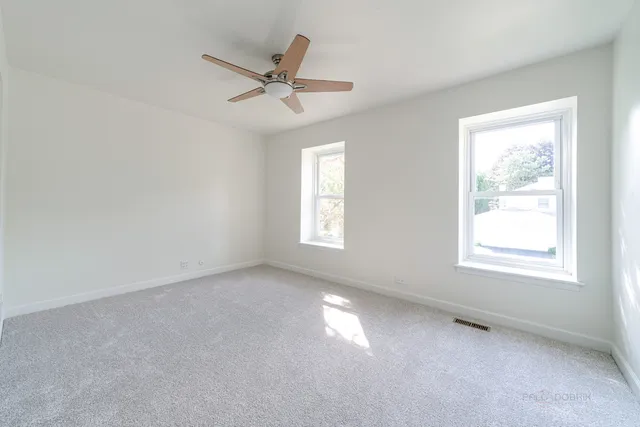 an empty room with a window and a fan