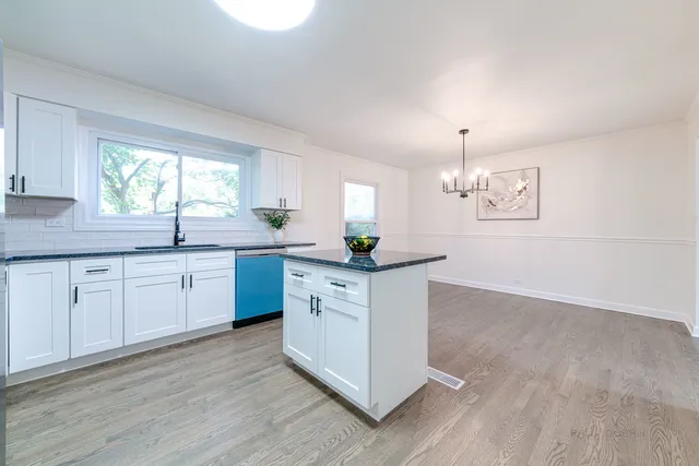 a kitchen with stainless steel appliances granite countertop a sink a stove and white cabinets with wooden floor