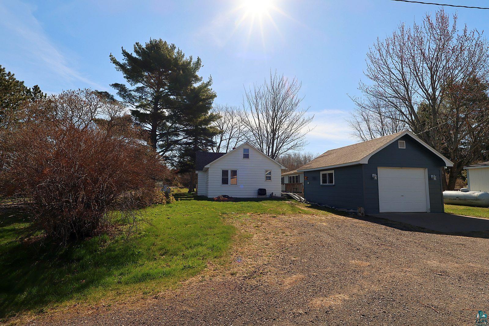 83185 Washington Avenue Port Wing, WI 54865 - Photo 3 of 26 White siding residence featuring a detached garage with a white overhead door and blue siding