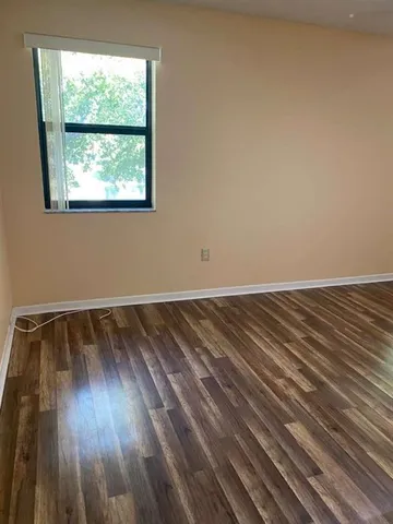 a view of an empty room with window and wooden floor