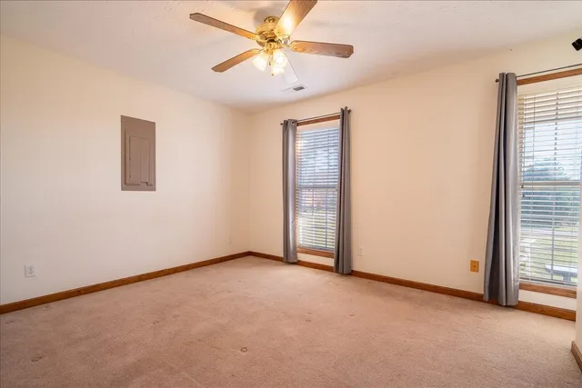 an empty room with windows and fan